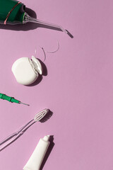 Dental care concept composition with toothbrush, tooth floss and toothpaste on the bright violet background. Copy space	