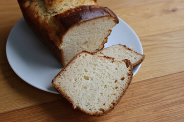 Homemade baked and sliced  Brioche Bread on a white plate on wooden table