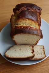 Homemade baked and sliced  Brioche Bread on a white plate on wooden table