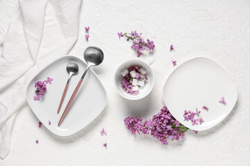Beautiful table setting with lilac flowers on white grunge background