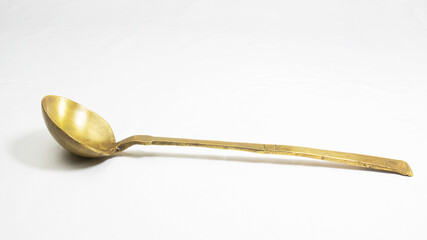 Empty golden brass spoon. traditional utensil for cooking and rituals during religious festivals. isolated in a white background.