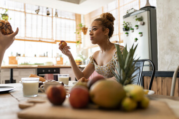 Young Woman Enjoying Fresh Fruit During a Friendly Breakfast Conversation