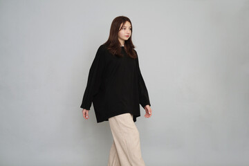 Confident woman strides forward in an oversized black shirt, epitomizing grace and modern fashion...