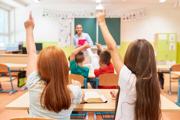 Schoolgirls raising hand in class