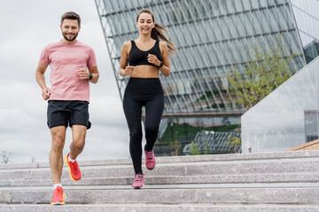A dynamic couple runs down the steps in an urban setting, their focused expressions and athletic...