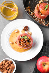 Tasty baked apples with nuts, honey and mint on gray textured table, flat lay