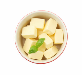 Tasty butter cubes and basil leaves in bowl isolated on white, top view