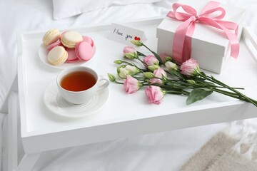 Tasty breakfast served in bed. Delicious macarons, tea, gift box, flowers and I Love You card on tray