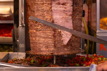 Close-up of a chef cutting meat with a doner knife for a traditional street food doner kebab or...