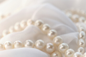 Pearls are scattered gracefully on a light backdrop, their muted glow symbolizing a soft elegance....