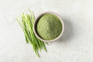Wheat grass powder in bowl and fresh sprouts on light table, flat lay