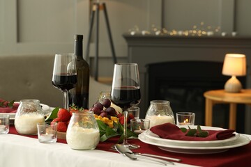 Stylish table setting with burning candles and wine indoors. Romantic dinner