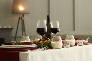 Stylish table setting with burning candles and wine indoors. Romantic dinner