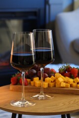Glasses of wine and tasty snacks on wooden table. Romantic dinner