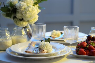Stylish table setting with candles and beautiful flowers