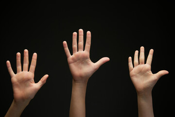 Image of teenager's, children's hands shows palms against black background. Hands raising up....