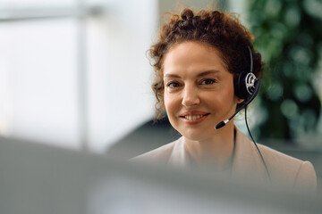 Smiling call center agent in office looking at camera.