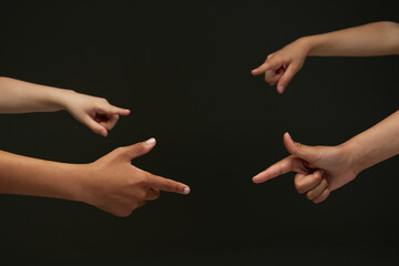 Closeup of diverse children's hands pointing, showing their index fingers against black background....