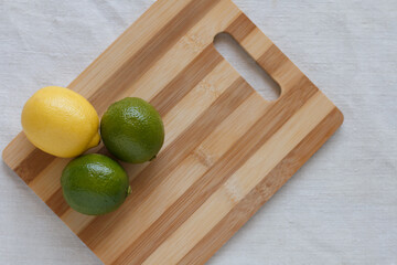 A lemon and two limes on a cutting board.