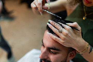 Close-up of a barber combing and styling a male client's hair, focusing on precision and detail in...