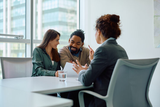 Happy couple reading terms of  agreement during  meeting with bank manager in office.