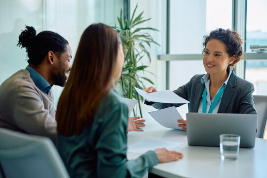 Happy insurance agent going through paperwork with her clients in office.