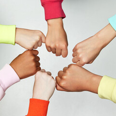 Teamwork. Close up of hands clenched in fist meeting join hands against against grey background....