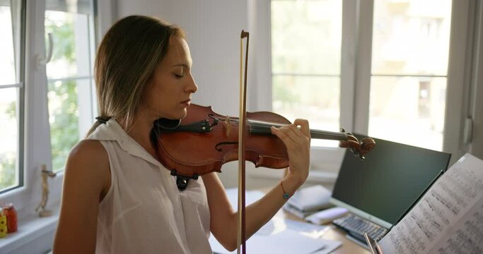 Young female violinist practicing violin at home