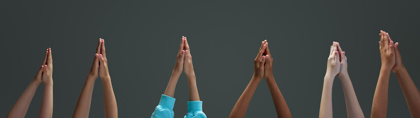 Pairs of kid's arms reaching upwards, their hands clasped in a gesture of unity and strength...