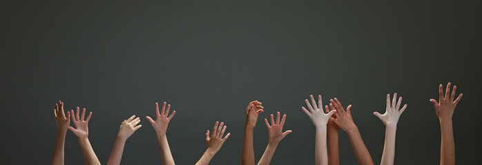 Hands of people, children of different races reaching upwards against gradient grey background. Panoramic image. Concept of youth, expression, beauty, emotions, gestures, art and symbolism, diversity