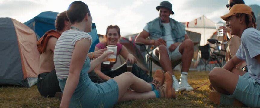 Friends cheering and toasting at a music festival campsite