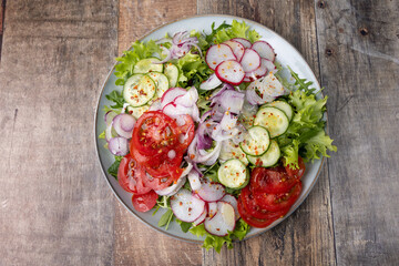 A plate of fresh chopped vegetables dressed with olive oil and spices. Vegetarian dish. Fresh vegetable salad in rustic style. Selective focus, close-up.