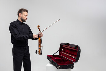 Bearded man artist packing musical instrument in violin case