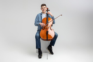 Young man wearing casual clothing playing cello © zinkevych