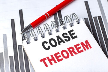 COASE THEOREM text on notebook on chart with pen