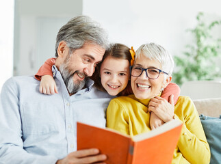 grandchild family child grandparent grandmother book reading elderly granddaughter girl  happy...