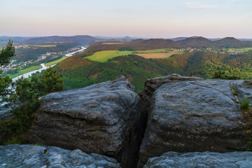Amazing view across the cliff to a rustic style with green meadows and fields, neat houses in the valley and the Elbe River. Saxon Switzerland National Park, Germany