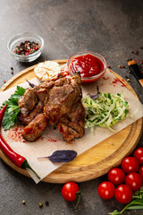 Pieces of grilled meat on a board and fresh vegetables