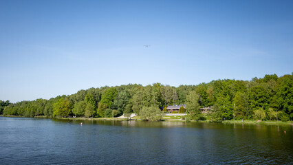 The valley of three ponds in Katowice. Restaurants on the lake shore. Airplane against the...