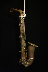 Saxofón colgado en fondo negro