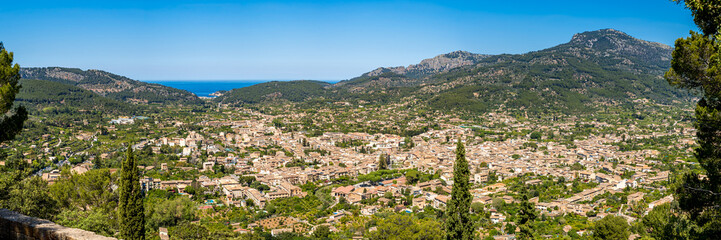 Obraz premium Panorama of Sóller, with Port de Sóller and the azure Mediterranean Sea, nestled in the lush Valley of Oranges amidst Serra de Tramuntana mountains, ideal for seekers of natural beauty and serenity.