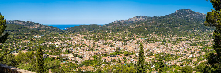 Panorama of Sóller, with Port de Sóller and the azure Mediterranean Sea, nestled in the lush Valley of Oranges amidst Serra de Tramuntana mountains, ideal for seekers of natural beauty and serenity.