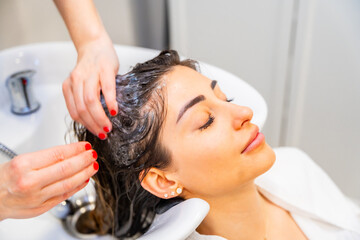Naklejka premium Hairdresser cleaning the hair of a relaxed woman