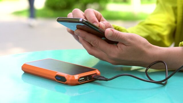 4k footage ogf Female hands using mobile phone while charging it with a portable power bank