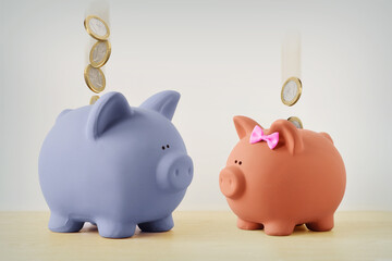 Blue and pink piggy bank with falling coins - Gender pay gap concept