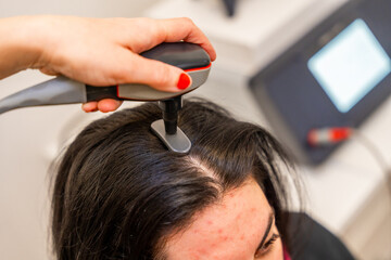 Hairdresser applying modern treatment to combat hair loss at woman