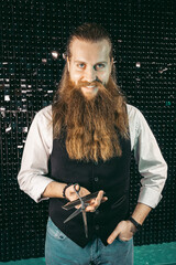 Bearded barber portrait with scissors .Man young barber hairdresser professional with long beard and hair in vest with scissors in hands portrait, cutting with scissors on black background. profession