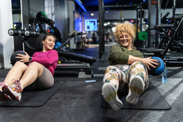 Two plus-size women workout and exercise with medicine ball at the gym. They're determined to achieve their goals and inspire others along the way.	
