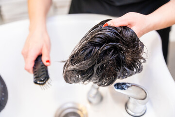 Hairdresser combing a wig after clean it in the salon