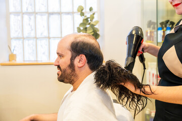 Hairdresser drying a washed capillary prosthesis of a client